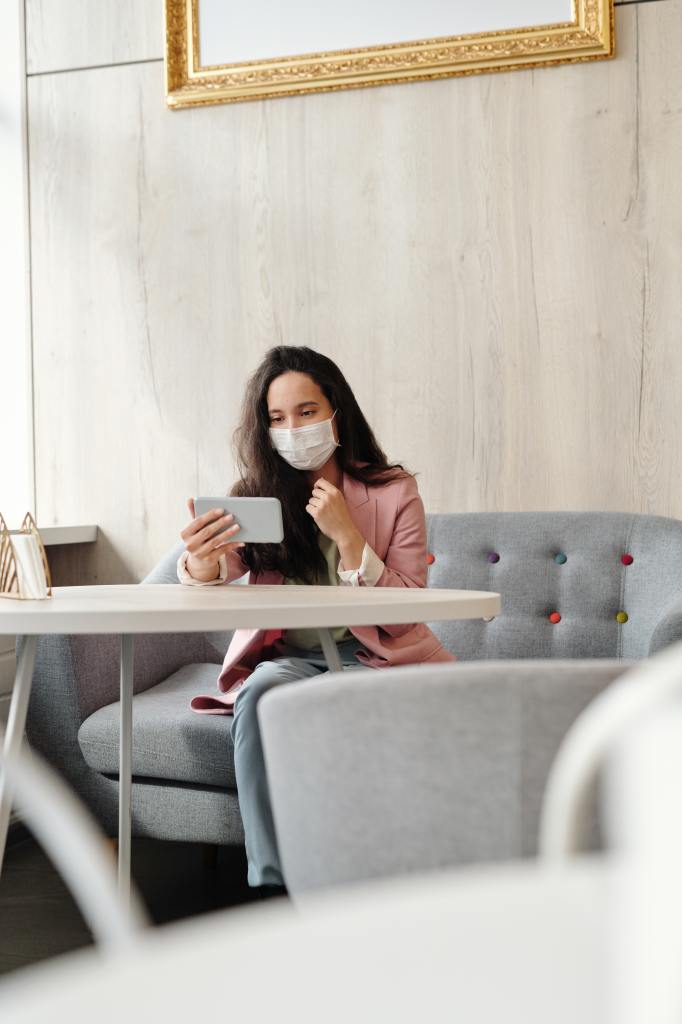 woman-wearing-a-face-mask-while-sitted-using-her-phone-4031816